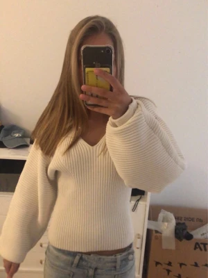 Vit ribbstickad tröja med v-ringning - Säljer en vit ribbstickad tröja med v-ringning och vida ärmar. Tröjan har en figurnära passform i midjan och är gjord i ett mjukt, stretchigt material.😍