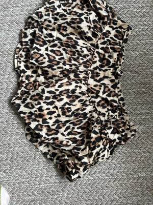 Leopardmönstrade shorts med volang - Säljer ett par snygga shorts med leopardmönster och volangdetaljer. De har en loose passform och resår i midjan för extra komfort. Perfekta för dig som vill sticka ut med ett djuriskt print.