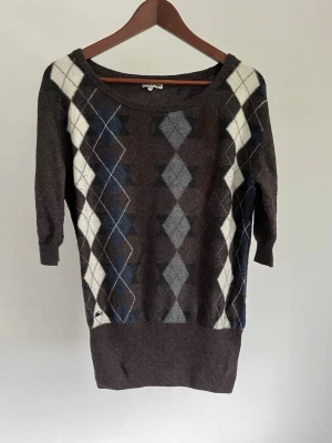 Lacoste stickad tröja (finstickad pullover) - Lacoste stickad tröja (finstickad pullover) Storlek: S Färg: Brun med klassiskt argyle-mönster Passform: Slim fit Krage: Rund hals (Crew Neck) Material: 35 % viskos 29 % ull 20 % polyamid 8 % kashmir 8 % angora Skick: Denna tröja är i ett väldigt fint skick utan defekter  Nypris cirka: 2 000 kr