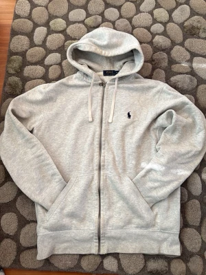 Grå hoodie från Ralph Lauren - Säljer en stilren grå hoodie från Ralph Lauren med dragkedja i bra skick har bara ett håll som man inte ser vid användning. Tveka inte att skriva om du har några frågor. Äkta. 