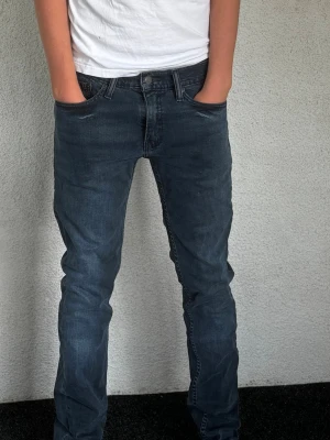Mörkblå slim fit jeans herr - Säljer ett par mörkblå slim fit jeans med klassisk femficksmodell och normalhög midja. Jeansen har snygga slitningar och raka ben. Materialet är mjukt denim som ger en skön känsla och bra passform. Perfekta till vardagslooken!