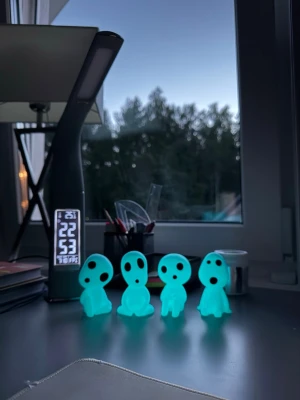 Glödande kodama figurer 4-pack - Säljer ett set med fyra självlysande kodama figurer inspirerade av Studio Ghibli. Figurerna är gjorda i plast och lyser i mörkret med en blågrön ton. Perfekta som dekoration på skrivbordet eller i bokhyllan för dig som gillar anime och unika detaljer.
