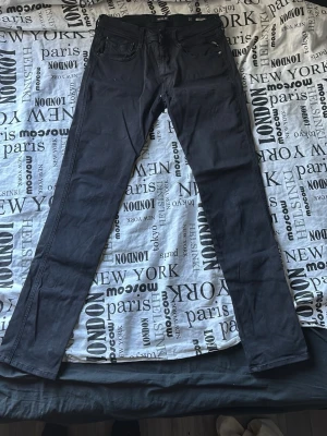 Svarta slim fit jeans från replay  - Säljer ett par svarta slim fit jeans med klassisk femficksdesign och dragkedjegylf. Jeansen har raka ben och är tillverkade i ett mjukt denimtyg som sitter snyggt på kroppen. Perfekta för en stilren och enkel look. Midja 31 längd 32
