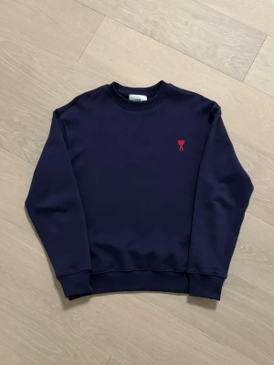 AMI Paris Sweatshirt blå - Säljer en stilren blå sweatshirt med rund hals och ribbade muddar. HELT NY! På bröstet finns en stor applikation med ett hjärta. Perfekt för dig som gillar enkel men snygg design. SKICKAS INOM 24 TIMMAR📦