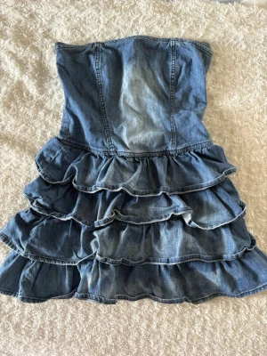 Jeansklänning med volanger - Axelbandslös jeansklänning med volanger och dragkedja i ryggen. Jättesöt klänning men kommer inte till använding💓