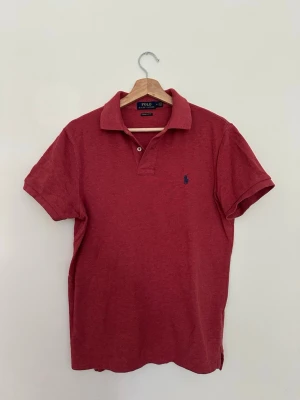 Röd pikétröja från Polo Ralph Lauren - Säljer en röd pikétröja från Polo Ralph Lauren med broderad blå logotyp på bröstet. Klassisk modell i hög kvalitet som passar både till vardag och mer uppklädda tillfällen. Använd ett fåtal gånger och är i nyskick. Nypris ca 1 200 kr.