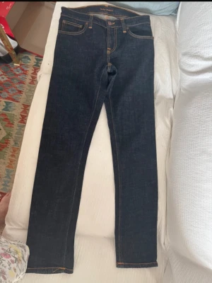 Mörkblå slim fit jeans - Säljer ett par mörkblå slim fit jeans med klassisk femficksmodell och kontrastsömmar. Jeansen har raka ben och är tillverkade i ett kraftigt denimtyg som ger en snygg och tidlös look. Perfekta till alla typer av outfits!