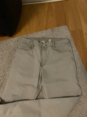 Ljusgråa slim fit jeans - Snygga ljusgråa slim fit jeans med klassisk femficksdesign och normalhög midja. Jeansen har raka ben och är tillverkade i ett mjukt denimtyg med stretch för extra komfort. Perfekta för en clean och stilren look.