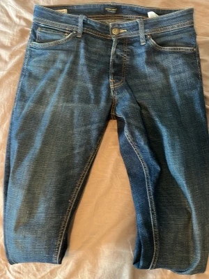 Blåa slim fit jeans med stretch - Snygga blåa slim fit jeans med klassisk femficksdesign och dragkedjegylf. Jeansen har en tvättad look med ljusa partier och kontrastsömmar. Tillverkade i stretchigt denimtyg för extra komfort.