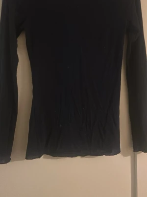 Svart långärmad topp i ull - Marinblå långärmad topp från intimismi  i tunn och mjuk jasmin tyg. Toppen har en slim passform och är perfekt att bära som lager under andra plagg. Enkel och stilren design utan synliga detaljer.
