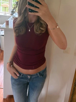 Mörkröd nelly topp - Säljer en snygg mörkröd topp med tight passform och korta ärmar från nelly i storlek XS, har använts några få gånger men ändå i riktigt bra skick! 