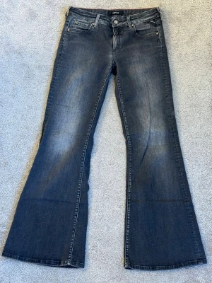 Mörkgrå bootcut jeans med utsvängda ben - Säljer ett par mörkgrå bootcut jeans med snygga detaljer och utsvängda ben. Klassisk femficksmodell med knapp och dragkedja framtill. Jeansen har en cool vintagekänsla. 