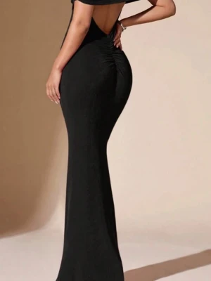 Svart långklänning med öppen rygg - Elegant svart långklänning med figurnära passform och öppen rygg. Klänningen har offshoulder-design. Använt en gång 