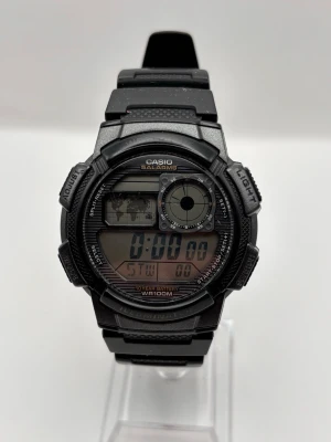 Svart digital sportklocka Casio - Digital sportklocka från Casio i svart plast med flera funktioner som alarm, stoppur och bakgrundsbelysning. Klockan har en robust design, tydlig digital display och justerbart armband. Perfekt för dig som gillar en aktiv livsstil och vill ha en klocka med många smarta funktioner.