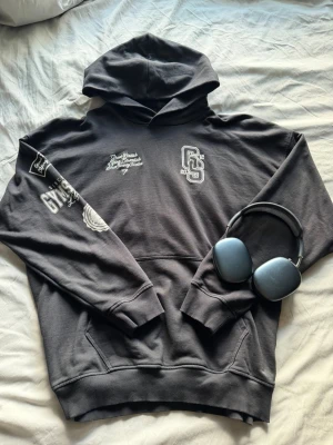  Gymshark hoodie  - Snygg svart hoodie från Gymshark med vita tryckdetaljer på bröstet och ärmen. Hoodien har en klassisk huva och känguruficka framtill. Perfekt för gymmet eller chill. Tjockt och mjukt material som känns riktigt skönt. Storlek L