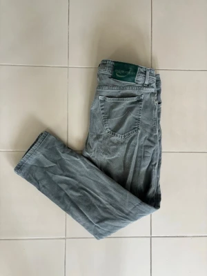 Jeans Jacob Cohen  - Säljer ett par jeans från Jacob Cohen i en oerhört stilig och unik grågrön färg. Väldigt sofistikerade jeans som man tydligt märker av att det är jeans av kvalitet! Badgen är otroligt fräsch och sällsynt precis som byxornas färg. Högst exklusiva byxor! Längd - 98 cm och bredd - 44 cm. Slå gärna en signal vid intresse!