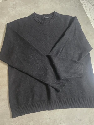 Svart stickad tröja från ZARA - Klassisk svart stickad tröja från ZARA med rund halsringning och ribbade muddar vid ärmslut och nederkant. Enkel och stilren design som passar till det mesta. Perfekt basplagg i garderoben.
