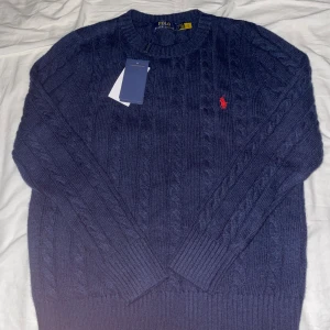 Mörkblå stickad tröja Polo Ralph Lauren - Säljer nu denna helt nya Ralph Lauren Cable Knit tröjan. Mörkblå och i storlek S. Helt ny, använd 3 gånger, lappen har jag t.om kvar. Om ni har några funderingar eller prisförslag är de bara att höra av sig! OBS: bilderna är ifrån när den är ny, men anvönd 3 gånger så ser ungefär likadan ut. Kan skicka nytagna bilder vid intresse.