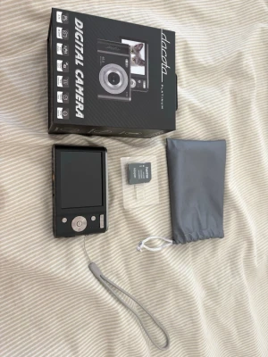Svart digitalkamera Daoda Platinum - Snygg svart digitalkamera från Daoda Platinum med stor display, enkla knappar och handledsrem. Kommer med originalkartong, grå förvaringspåse och minneskort. Perfekt för dig som vill ta bilder snabbt och smidigt. Kameran har en kompakt och stilren design i plast.