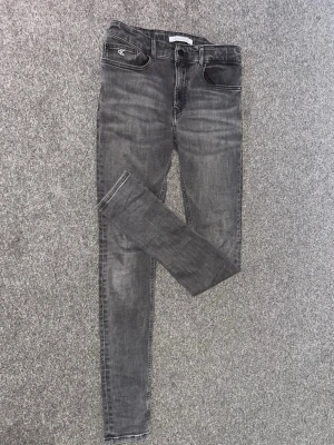 Calvin Klein jeans - Snygga grå jeans från Calvin Klein med klassisk femficksdesign och logga på bakfickan. Jeansen har en smal passform och är tillverkade i mjuk bomull med lite stretch för extra komfort. Perfekta till en avslappnad streetstyle-look.
