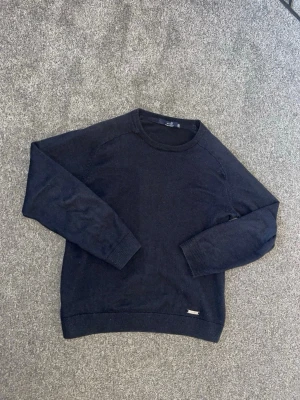 Pele P tröja - Mörkblå pele P stickad tröja i mjuk bomull med rund halsringning och ribbade muddar vid ärmslut och nederkant. Enkel och stilren design som passar till det mesta. Perfekt för dig som gillar klassiska plagg med en clean look. Pris kan diskuteras