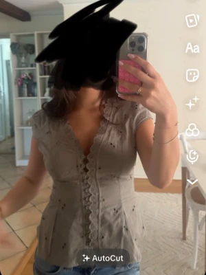 Grön blus med spetsdetaljer - Söt grön blus med broderade hål och spets längs v-ringningen och knappraden. Modellen har korta ärmar och figurnära passform. Perfekt att styla med jeans för en trendig look. Använd en gång, Skriv för fler bilder!!