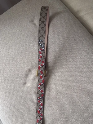 GG snake bälte  - Snyggt bälte med klassiskt GG-mönster och en cool orm i rött, vitt och svart längs hela bältet. Spännet är i guldton och bältet är gjort i skinn. Perfekt accessoar för att lyfta vilken outfit som helst.