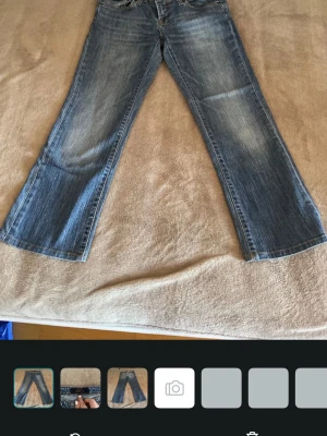 Blå bootcut jeans från Cubus - Säljer ett par blå bootcut jeans från Cubus i klassisk denim med snygga slitningar framtill. Jeansen har normal midja, fem fickor och kontrastsömmar. Perfekta för dig som gillar en avslappnad men trendig look.