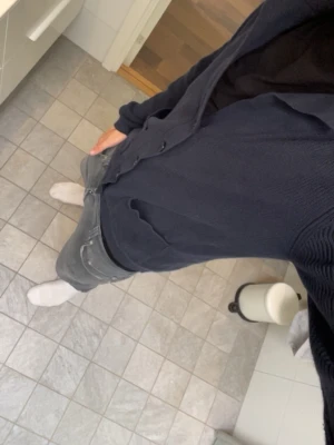  Dressman Mörkgrå stickad kofta med knappar - Mysig mörkgrå stickad kofta med v-ringning och fem knappar framtill. Två praktiska fickor på framsidan och långa ärmar. Perfekt att slänga på sig över en t-shirt eller skjorta för en avslappnad look.