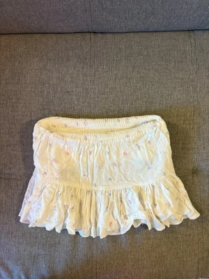 Vit blommig kjol med volang - Vit kjol med små blommor och volang nertill.