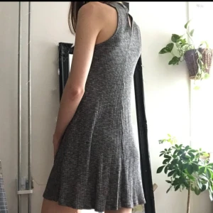 Hollister ribbstickad klänning - Gråmelerad, ribbstickad klänning från Hollister märkt M (det är en liten M och känns mer som en S). 65% viskos 35% polyester. Halvpolo som knäpps med två knappar baktill, assymetrisk nedtill. Använd ett fåtal gånger - i gott skick 🤍 1:a bilden lånad.