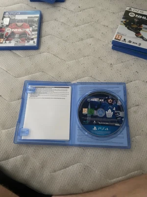 NHL 22 till PS4 - NHL 22 till PlayStation 4 i blå plastfodral. Ishockeyspel från EA Sports med omslag i blått och vitt, där en spelare från Toronto Maple Leafs syns. Spelet har PEGI 12-märkning och inkluderar SHL och Liiga. Perfekt för dig som gillar sportspel och hockey.