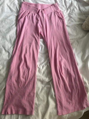 Rosa mjukisbyxor med fjäril - Säljer ett par ljusrosa mjukisbyxor med broderad silverfjäril framtill. Byxorna har bred resår i midjan och raka ben. Tillverkade i mjukt och stretchigt material som är skönt att ha på sig. Perfekta för chill dagar eller när du vill vara extra comfy.