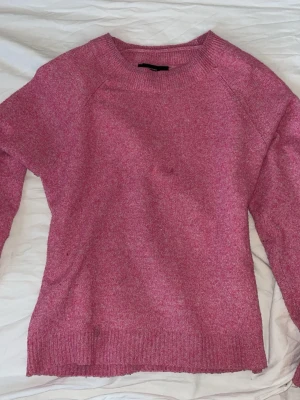 Rosa stickad tröja med rund hals - Mysig rosa stickad tröja med rund halsringning och långa ärmar. Tröjan har ribbstickade muddar vid ärmslut och nederkant. Perfekt för att hålla värmen under kyliga dagar och enkel att matcha med olika outfits. lite nopprig