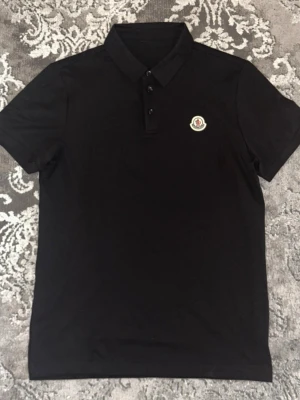Moncler pike - Fin stilren Moncler pikétröja svart, nyskick testad bara. Perfekt med shorts eller fin byxa för en stilren o clean look, pris kan diskuteras vid snabb affär.