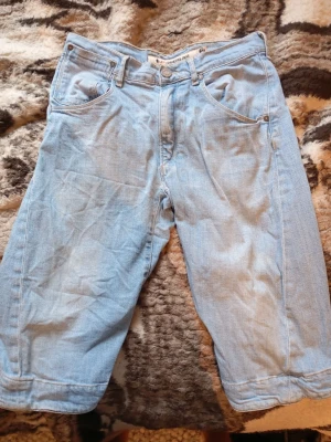 Ljusblå jeansshorts från Levis  - Säljer ett par ljusblå jeansshorts från Levis i klassisk modell med fem fickor och bälteshällor. Shortsen har en lös passform och är tillverkade i denim. Perfekta för en avslappnad stil under varma dagar. Använda 1 gång. Jag är 180 cm lång. Dom är lite för långa för mig, så passar nog dom som är 185 cm. Pris kan diskuteras🙌. Mvh Rasmus.