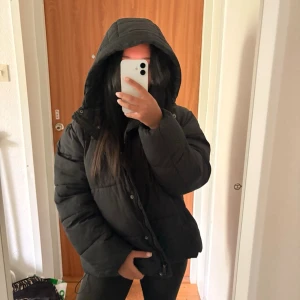 Mörkblå pufferjacka från 157 - Säljer en mörkblå pufferjacka från 157 i storlek M. Jackan har en stor huva, dragkedja framtill och är riktigt fluffig och varm. Perfekt för kalla vinterdagar och har en klassisk, oversized look. Materialet är glansigt och tåligt mot vind.