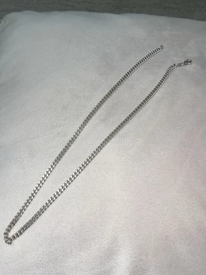 Kedjehalsband i silverfärg - Snyggt halsband i silverfärgad metall med klassisk kedjedesign. Halsbandet har en enkel karbinhake och passar perfekt för dig som gillar stilrena accessoarer. Lätt att matcha med olika outfits och ger en clean look.