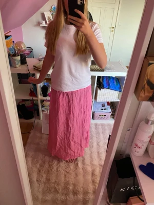 Rosa långkjol i bomull - En enkel och snygg rosa långkjol i mjukt bomullstyg. Kjolen har en rak passform och är perfekt för dig som gillar en avslappnad men ändå stilren look. Passar till både t-shirt och crop top för en chill vibe.