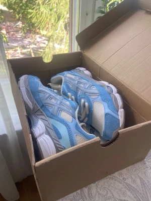 Blå och vita sneakers med meshdetaljer - Snygga sneakers i ljusblått och vitt med meshpaneler för extra ventilation och detaljer i mockaimitation. Skorna har en chunky vit sula och klassisk snörning. Perfekta för dig som gillar sportig stil och vill sticka ut med fräscha färger.