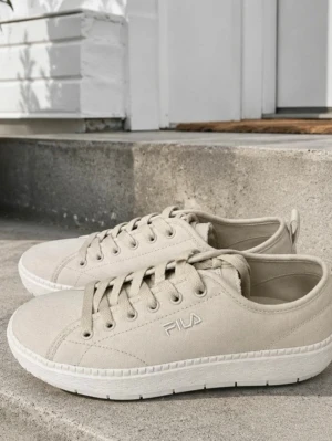 Oanvända storlek 37 Beige sneakers från FILA - Oanvända nya Snygga beige sneakers från FILA med klassisk låg profil och vita sulor. Skorna har textilöverdel, ton-i-ton snörning och diskret FILA-logga på sidan. Perfekta för en clean och stilren look.