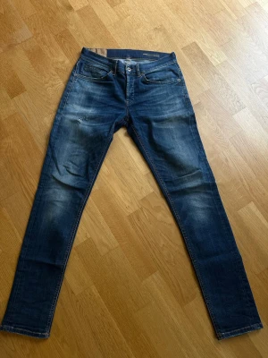 Mörkblå Dondup Geroge jeans - Snygga mörkblå jeans från Dondup i modellen George. Slim fit och har en lite slitningar på både fram och baksida. 