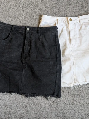 Två jeanskjolar i svart och vitt - Säljer två snygga jeanskjolar, en svart och en vit. Båda har klassisk femficksdesign, knapp och dragkedja framtill samt rå kant nertill för en trendig look. Perfekta att matcha med en crop top eller hoodie.
