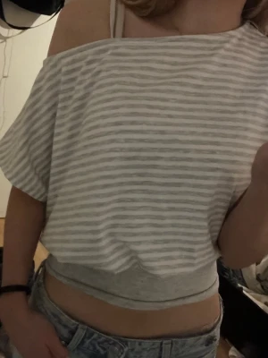 Randig offshoulder topp i bomull - Säljer en ljusgrå och vit randig offshoulder topp med mudd i midjan💞