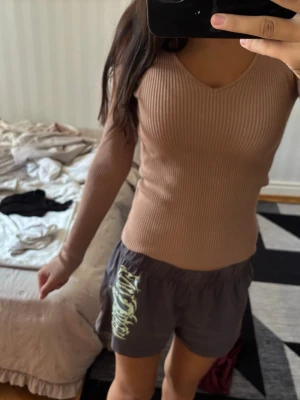Beige ribbad stickad tröja Amisu - Säljer en beige, ribbad stickad tröja från Amisu. Tröjan har lång ärm, v-ringad hals och är tillverkad i ett mjukt, stretchigt material som sitter snyggt på kroppen. Perfekt för lager på lager och enkel att matcha med olika outfits.