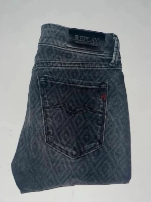 Replay jeans  - Snygga Replay jeans i mörkgrått med coolt geometriskt mönster över hela byxan. Midja 32cm, längd 101cm. JAG SKICKAR EJ FLER BILDER NÄR JAG BÄR JEANSEN! för bättre inblick i passformen rekommenderar jag att googla på modellnamnet. För storleksguide kolla måtten noggrant då jeansen alltid kan vara uppsydda heller krympta och jag ej tar emot returer :) (r28)