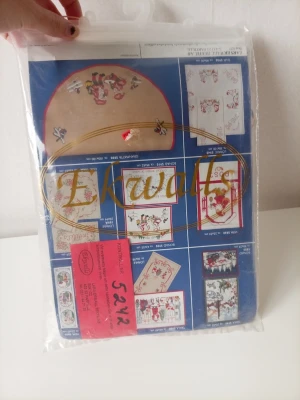 Broderikit med röd ram Ekwalls - Broderikit från Ekwalls med mönster, instruktioner och en rektangulär röd ram. Kitet innehåller olika broderimotiv med färgglada illustrationer och tyg. Perfekt för dig som gillar handarbete och vill skapa egna dekorationer.