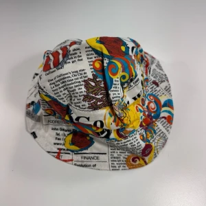 John Galliano Färgglad bucket hat med tidningsmönster - Cool bucket hat med tidningsinspirerat tryck! 0673