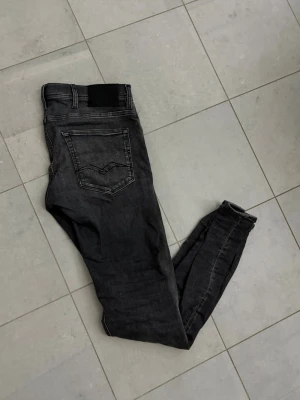 Svarta jeans från Replay - Säljer ett par svarta skinny jeans från Replay med klassisk femficksdesign och dragkedjegylf. Jeansen har en lätt tvättad look och smal passform som sitter snyggt. Perfekta för dig som gillar en stilren och modern vibe. OBS: det har funnits ett hål vid skrevet som är lagat men det är inget som syns när man bär dom. Jeansen är i bra skick men det finns små fläckar 