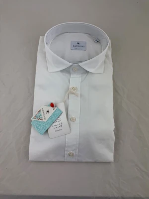 Vit klassisk skjorta Bastoncino - Snygg vit skjorta från Bastoncino med klassisk krage och knappar framtill. Tillverkad i mjuk bomull för en skön känsla och stilren look. Perfekt till både jeans och kostymbyxor. Enkel och tidlös design som passar till många tillfällen.